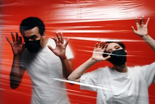 Two people in masks behind plastic barrier