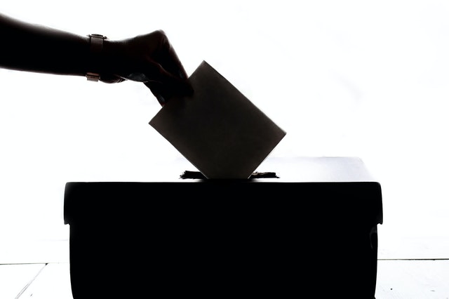 Voter drops a ballot into the ballot box.