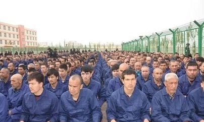 Hundreds of Uyghur Muslim prisoners assemble outdoors for re-education lectures.